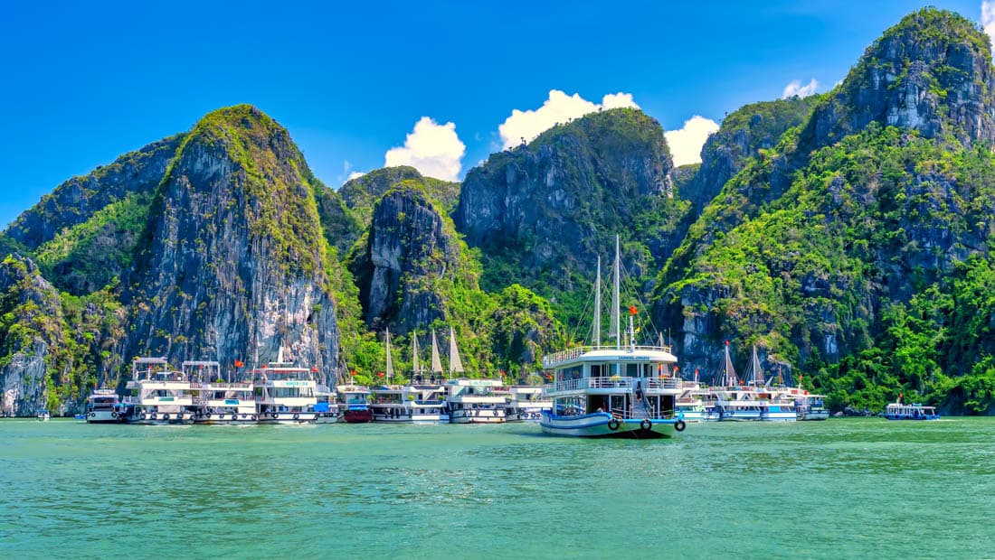 Plusieurs jonques et bateaux de croisière navigant dans la baie d'Halong, Vietnam